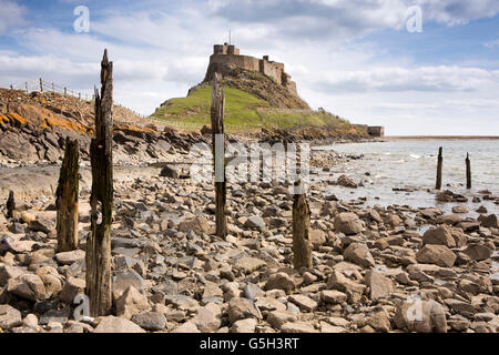 Regno Unito Inghilterra Northumberland, Isola Santa Lindisfarne Castle e resti di pontile in legno sulla riva Foto Stock