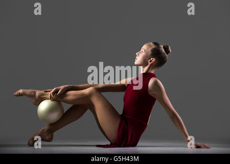 Bella giovane montare ginnasta atleta donna abbigliamento sportivo in abito rosso che lavora fuori, fare arte ginnastica esercizio Foto Stock