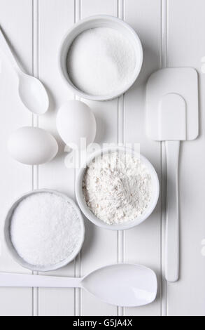 Tutto bianco la cottura ancora in vita. Gli elementi includono: spatola, frusta, uova, farina, sale, zucchero, ciotole e cucchiai. Formato verticale shot fro Foto Stock