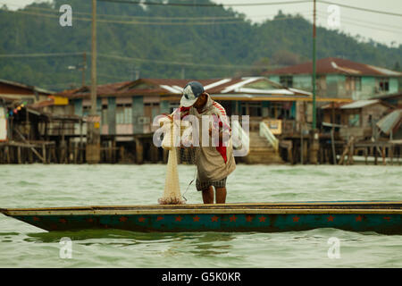 Pescatore pesca in mare, Kampong Ayer, Brunei Foto Stock