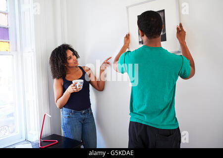 Giovane appendere foto nel nuovo appartamento Foto Stock