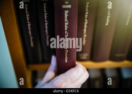 La donna caucasica selezionando il libro di riferimento dal ripiano Foto Stock