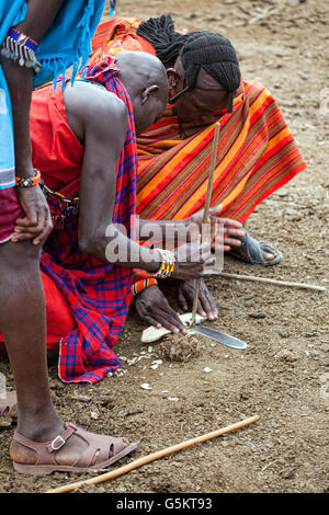 Un gruppo di giovani guerrieri Masai innescando un incendio nel villaggio dei masai in Kenya, Africa. Foto Stock