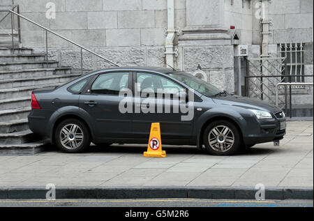 Una macchina parcheggiata sul marciapiede accanto a un ansa giallo "No parcheggio' cono stradale, città di Cork, nella contea di Cork, Irlanda (Eire). Foto Stock