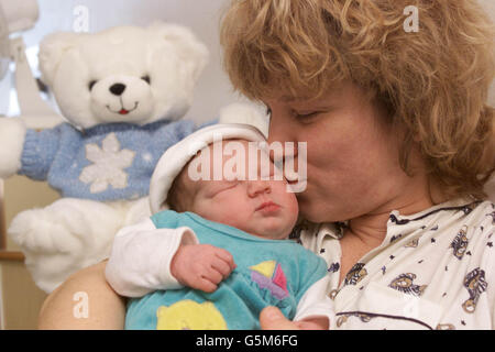 Anne Meier bacia dolcemente sua figlia Rea nata alle 12:30 di questa mattina, Capodanno al St Mary's Hospital di Portsmouth, Hampshire. Il personale di sicurezza ha acquistato un orsacchiotto (a sinistra) per celebrare l'occasione del primo bambino dell'ospedale nel 2002. * Rhea non era dovuto per un'altra settimana ed è stato consegnato dalla sezione cesarea. Foto Stock