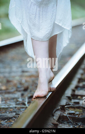 La donna caucasica equilibrio sui binari del treno Foto Stock