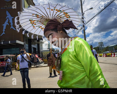 Mahachai, Samut Sakhon, Thailandia. Il 23 giugno, 2016. Un uomo vestito come un tradizionale birmana street performer riposa in attesa di Aung San Suu Kyi per arrivare a Samut Sakhon, una provincia a sud di Bangkok. Decine di migliaia di lavoratori birmani immigrati, la maggior parte degli impiegati nella pesca tailandese industria, vivere in Samut Sakhon. Aung San Suu Kyi, il ministro degli Affari Esteri e consigliere di Stato per il governo di Myanmar (un ruolo simile a quello del Primo Ministro o di un capo di governo), è in visita di stato in Tailandia. Anche se lei e il suo partito ha vinto le elezioni 2015 da una frana, ella è costituzionalmente Foto Stock