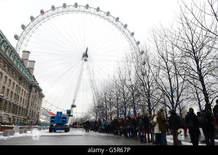 1000 persone hanno sfidato le condizioni meteorologiche avverse al EDF Energy London Eye questa mattina, accodandosi nella neve per la riapertura dell'"Lift London" e per una rotazione libera. Foto Stock