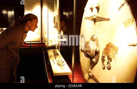 Un visitatore guarda una spada e uno scudo che si ritiene appartengano al guerriero di Raedwald Ling of the East Angles durante l'apertura del nuovo centro espositivo e del tesoro del National Trust a Sutton Hoo a Suffolk. * ... La mostra e il tesoro raccontano la storia delle sepolture rituali dei re pagani, di come vivevano gli anglosassoni, delle loro credenze religiose e di come i tesori furono scoperti nel sito del nuovo centro, più di 60 anni fa. Foto Stock