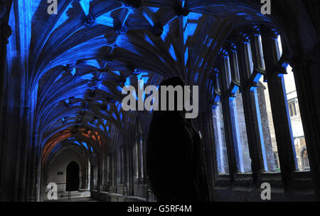 Il volontario del National Trust Kristine Heuser vede i chiostri di Lacock Abbey, dove sono state girate le scene di Harry Potter, che è stato illuminato da specialisti dell'illuminazione per l'illuminante Lacock Festival, Wiltshire. Foto Stock