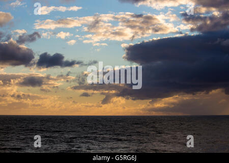 Un vago tramonto in un buio Australian cielo sopra il mare incolore a Ocean Beach, Bunbury, Western Australia nel tardo inverno . Foto Stock