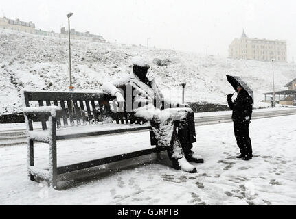 Un uomo studia la scultura di Freddie Gilroy e degli straggler Belsen ricoperti di neve di Ray Lonsdale a Scarborough, mentre la neve ha colpito oggi parti dell'Inghilterra con un massimo di 10 cm (4 poll.) che si prevede cadano in alcune aree, provocando timori di caos di viaggio. Foto Stock