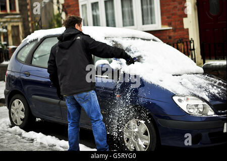 Un uomo libera la neve di due giorni dal parabrezza della sua auto a Bristol. Foto Stock