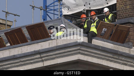 La polizia parla con i manifestanti di Greenpeace vestiti come operai siedono sul tetto dell'alloggio del Gabinetto al 22, Whitehall, Londra. Gli attivisti stanno mostrando porte fatte di legno tropicale che dicono sono in attesa di installazione nelle sale del gabinetto. *... e che gli attivisti affermano di essere fatti di legname proveniente da antiche foreste del Camerun nell'Africa occidentale. I 40 attivisti hanno dichiarato che l'uso del legno è stato contrario a un impegno del primo ministro Tony Blair di utilizzare fonti legali e sostenibili. Foto Stock