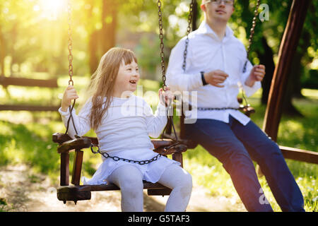 Bambino felice con la sindrome di down godendo di swing sul parco giochi Foto Stock