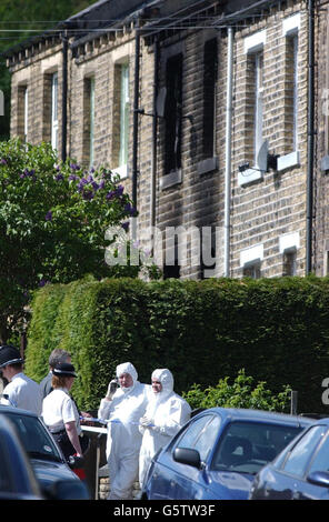 Gli ufficiali preposti della polizia esaminano una casa a Huddersfield, nello Yorkshire occidentale, dopo che questa mattina è scoppiato un incendio in cui sei persone, tra cui cinque giovani sorelle, sono morte. Foto Stock