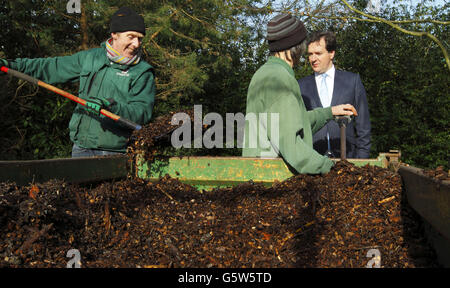 Il Cancelliere dello scacchiere George Osborne (a destra) osserva come i giardinieri spargettero pacciame nei terreni del campus di JP Morgan, a Bournemouth, dopo che ha tenuto un discorso sulla riforma bancaria al campus. Foto Stock