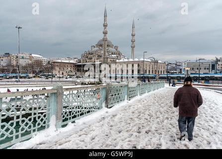 Attraversando una coperta di neve il ponte Galata in inverno con la Yeni o nuova moschea in background. Istanbul, Turchia. Foto Stock
