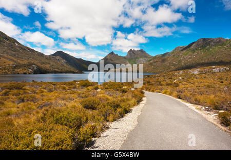 Un sentiero conduce in una vista di Cradle Mountain attraverso Colomba lago in una giornata di sole. La Tasmania, Australia. Foto Stock