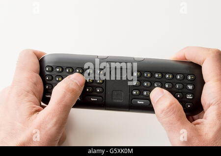 L'uomo le mani tenendo un tastierino del telecomando Foto Stock