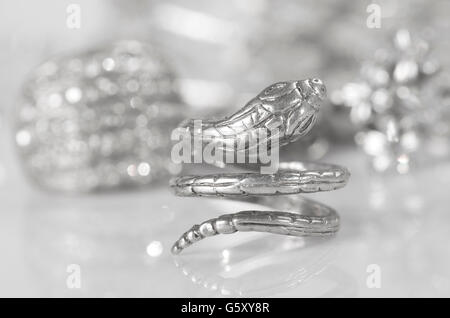 Anello in argento a forma di serpente e altri gioielli. Foto Stock