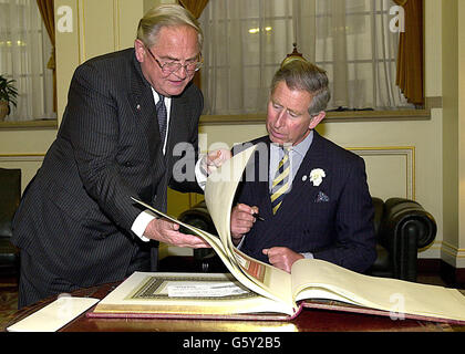 Il Principe del Galles (seduto) durante una visita alla Banca d'Inghilterra nella Città di Londra, per promuovere il Princes Trust, si siede giù per firmare il libro dei visitatori con la guida di Sir Eddie George, Governatore della Banca d'Inghilterra. Foto Stock