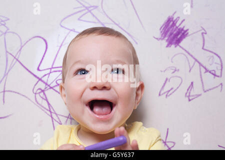 Smilling baby boy con pastelli a cera. Egli è alla ricerca per la fotocamera Foto Stock