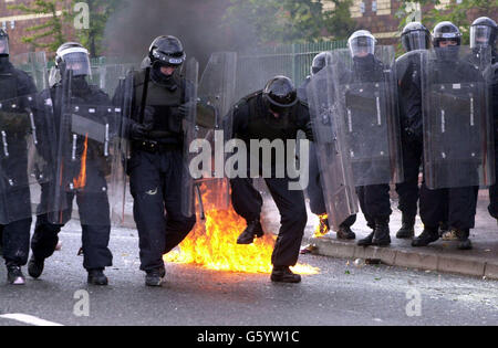 Un poliziotto estizza le fiamme dopo essere stato colpito da una bomba a benzina sulla Springfield Road, a ovest di Belfast. La polizia ha sofferto una sbarramento di bombe a benzina, fuochi d'artificio e mattoni dopo che gli ufficiali hanno sparato un bastone di plastica ai dimostranti che hanno attaccato una parata di ordine arancione in un'area nazionalista. I problemi sono iniziati quando i manifestanti cattolici hanno visto Orangemen salire su una parte contesa della Springfield Road. Foto Stock