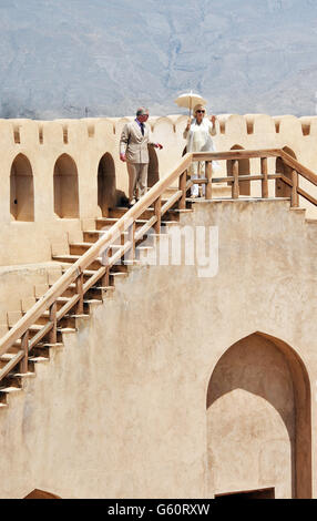 Il Principe di Galles e la Duchessa di Cornovaglia si ergono sui merli e ammirano la vista, durante la loro visita al Forte di Nizwa il secondo giorno del loro tour di Oman. Foto Stock