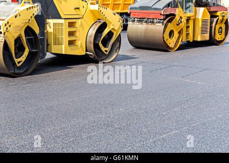 Strada di vapore rulli compattatori di asfalto fresco durante la guida su strada con lavori di riparazione Foto Stock