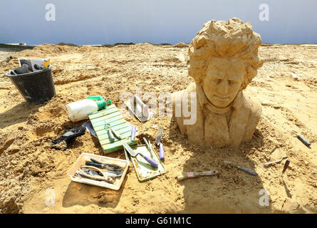 Una visione generale come scultori mettere il tocco finale di sculture di sabbia a tema musicale prima dell'inizio del festival 'Sing-a-Song of Sculpture' a Brighton. Foto Stock