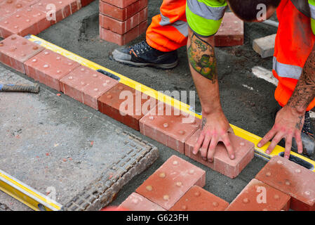 Workman posa di pavimentazioni tattili nel sentiero per assistere i non vedenti Foto Stock