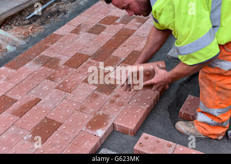 Workman posa di pavimentazioni tattili nel sentiero per assistere i non vedenti Foto Stock