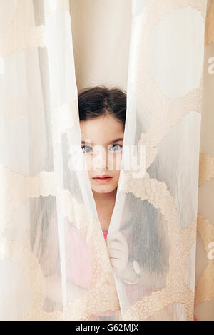 Bambina dietro la cortina Foto Stock