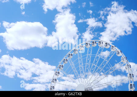 White ruota panoramica Ferris contro il blu cielo nuvoloso con copyspace su di esso Foto Stock