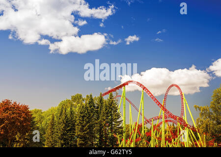 Estate theme park tonica paesaggio con montagne russe e blu cielo nuvoloso Foto Stock