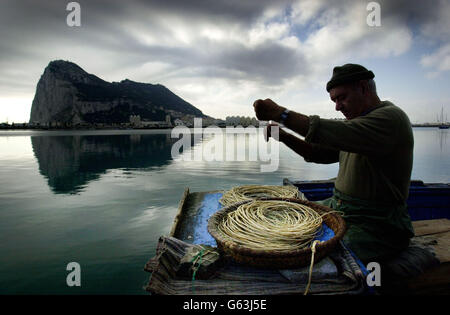 Un pescatore sul lato spagnolo di Gibilterra fissa ganci alle sue reti, prima dell'imminente referendum sulla sovranità congiunta dell'isola il 7 novembre. Foto Stock