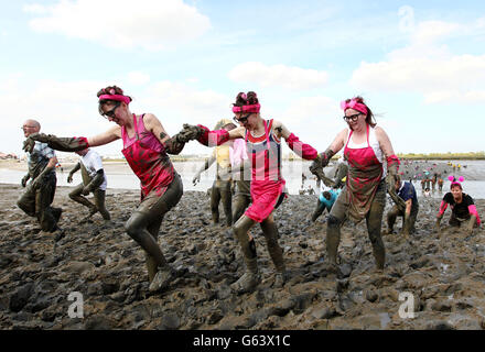 I concorrenti si arrampicare sulla riva del fiume fino al traguardo della gara annuale Maldon Mud a Maldon, Essex. Foto Stock