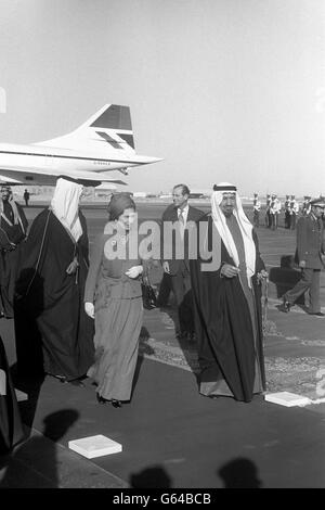 La Regina e il Duca di Edimburgo (dietro) sono stati accolti dal re Khalid all'aeroporto di Riyadh all'inizio della loro visita in Arabia Saudita, l'ultima tappa del loro tour di tre settimane del Medio Oriente. Indossa un lungo abito blu zaffiro che la copre dalla testa ai piedi. Ciò è stato in conformità con la legge islamica - rigorosamente osservata dai sauditi - che richiede che una donna non deve mostrare né le sue caviglie né le sue braccia. Foto Stock