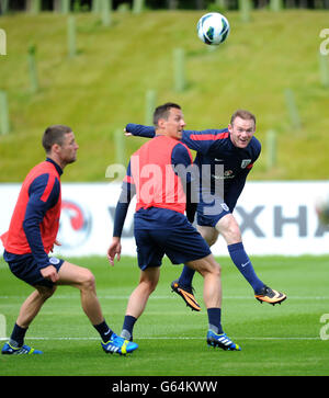 Wayne Rooney (a destra) in Inghilterra combatte per la palla con Phil Jagielka e Gary Cahill (a sinistra) durante una sessione di allenamento al St George's Park, Burton Upon Trent. Foto Stock