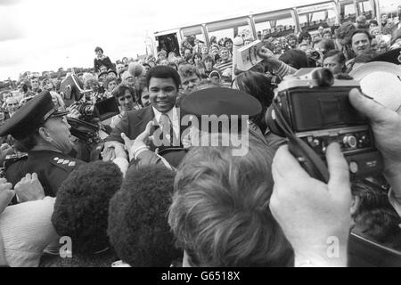 I poliziotti ansiosi circondano il campione del mondo della boxe pesante Muhammed Ali, mentre viene accolto da una folla enorme all'aeroporto di Newcastle. Ali, che ha volato con sua moglie Veronica e la loro figlia di 11 mesi, Hana, da Chicago questa mattina, aveva tenuto la folla in attesa di oltre cinque ore perché aveva perso il suo collegamento dall'aeroporto di Heathrow. Il pugile campione stava viaggiando nel Nord Est per visitare i club di boxe dei ragazzi attraverso Tyneside e contribuire a raccogliere soldi per loro. Foto Stock