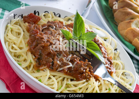 Italiano tradizionale piatto di spaghetti alla bolognese/bolognese servita con pane all'Aglio/Baguette e parmigiano grattugiato. Foto Stock