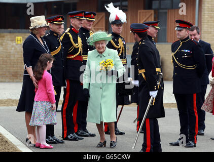 La regina Elisabetta II riceve un bouquet da Alice Edwards, di sei anni, quando arriva per incontrare i membri della truppa del re Royal Horse Artillery durante la sua visita alla Royal Artillery Barracks a Londra. Foto Stock