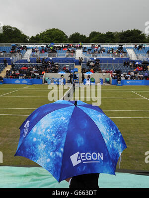 Gli spettatori prendono la copertura sotto gli ombrelli mentre il personale a terra si prepara a portare le coperture sul campo centrale prima di qualsiasi gioco nella semifinale tra Magdelana Rybarikova e Donna Vekic. Foto Stock