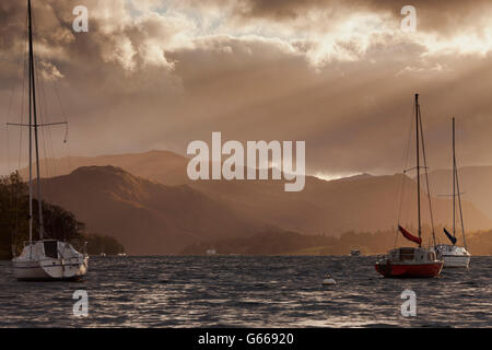 Vista di Hallin cadde, illuminato dal sole autunnale, con barche sull'Ullswater in primo piano, Pooley Bridge, Cumbria, Inghilterra Foto Stock