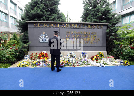 Un ufficiale della polizia metropolitana guarda le corone lasciate in tributo ad oltre 650 ufficiali che sono morti in servizio dalla formazione del MPS nel 1829, dopo la cerimonia di ricordo del Metropolitan Police Service (MPS), nel Memorial Garden presso il quartier generale di addestramento del Metropolitan Police Peel Center a Hendon, Colindale, Londra. Foto Stock