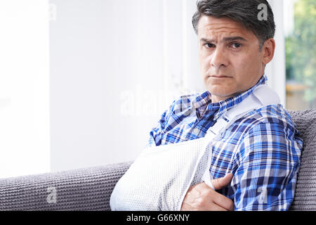 Ritratto di uomo maturo con il braccio in imbracatura a casa Foto Stock