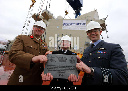 (Da sinistra a destra) colonnello Stuart Barnard dell'Army Air Corp, Il CAPT Dickie Payne della Royal Navy e il Capitano del Gruppo David Bradshaw della RAF con una targa con gli emblemi della Royal Navy, della Royal Air Force e dell'esercito britannico che saranno incorporati nel tessuto della HMS Queen Elizabeth portaerei dopo l'isola DI POPPA è stato Abbassato in posizione presso il cantiere di Rosyth di Babcock. Foto Stock