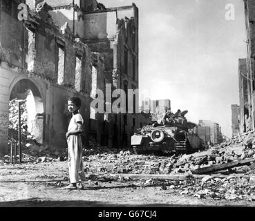 Un ragazzo egiziano fa un'indagine sulla devastazione mentre un carro armato britannico si muove attraverso una strada in rovina a Port Said, ora occupato dalle truppe anglo-francesi in attesa della forza di polizia delle Nazioni Unite Foto Stock