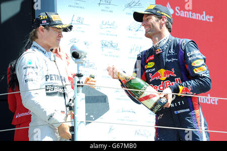 Il driver Mercedes AMG Petronas Nico Rosberg viene spruzzato con champagne da Mark Webber dopo aver vinto il Gran Premio di Santander britannico 2013 al circuito di Silverstone, Towcester. Foto Stock